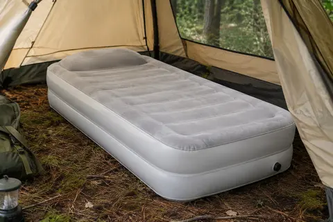Matelas gonflable blanc une place avec surface floquée et oreiller intégré, installé dans une tente en sous-bois.