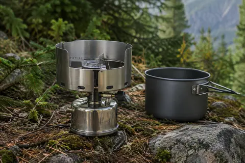 Réchaud de camping Super Carena en acier inoxydable avec pare-vent intégré, installé dans un sous-bois