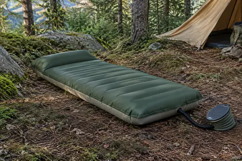 Matelas gonflable JATEKA vert militaire avec oreiller intégré posé sur un sol forestier