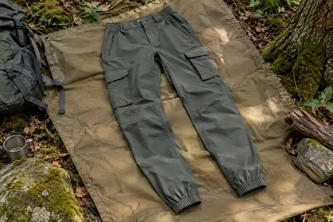 Pantalon cargo de randonnée léger avec poches zippées et chevilles élastiques posé dans un sous-bois.