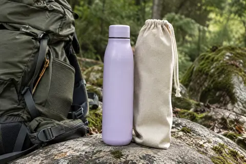 Gourde isotherme Nuactiv lilas en acier inoxydable avec sa housse en coton, posée en sous-bois