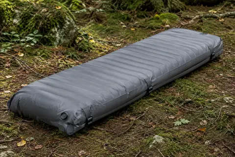 Matelas de bivouac PHYSEN gris avec pompe intégrée et sangles, installé sur un sol de sous-bois.