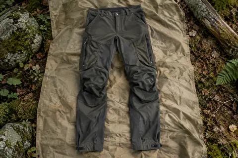Pantalon de randonnée homme avec poches, zips d’aération aux cuisses et bas de jambes réglables, posé en sous-bois.