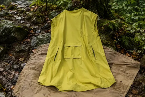 Poncho de pluie citron VAUDE Valdipino, ample et léger, posé dans un sous-bois humide.