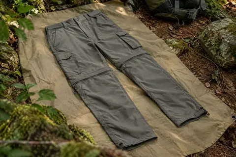 Pantalon cargo convertible de randonnée posé dans un sous-bois, avec poches visibles et jambes zippées